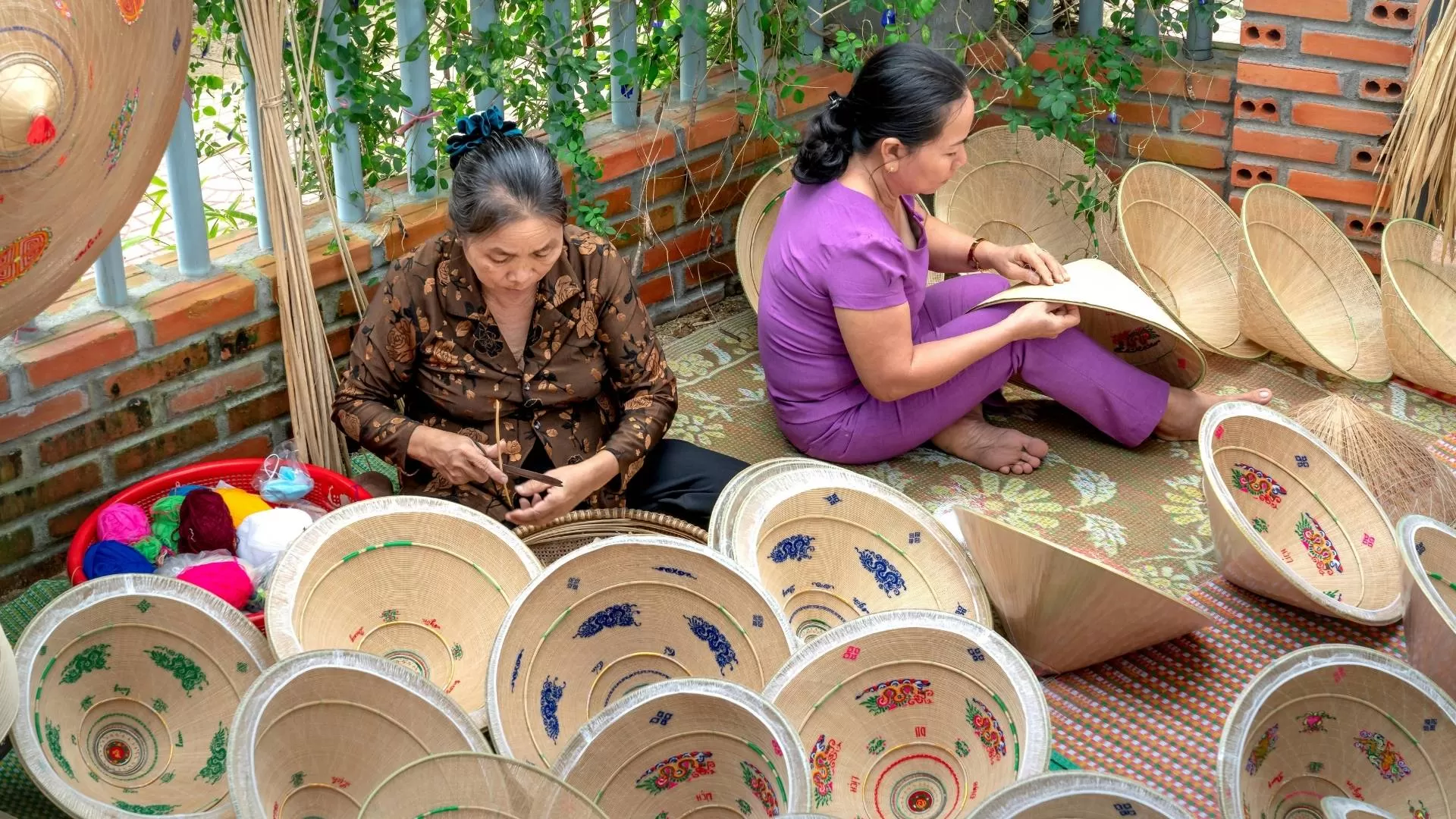 Artisan weaving a traditional Hue palm hat.